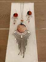 Front view of necklace pendant and earrings showing agate stones, silver tone metal designs, and dangling bead and charm details