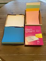 Overview showing stacks of letter size file folders in various colors with full box of envelopes and colored paper held in a box