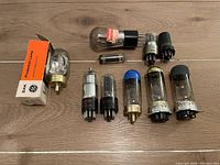 Assortment laid out on wooden surface showing vacuum tubes and lamp bulbs, including original GE box.