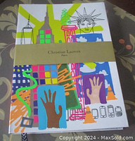 Front cover showing colorful New York-themed pop art design including cityscape, Statue of Liberty, hands and abstract motifs, wrapped with cream colored band reading 'Christian Lacroix Paris'.