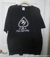 Front view of black Foo Fighters T-shirt showing full print logo and size tag.