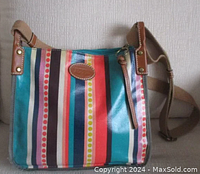 Front view of multicolored striped coated canvas Fossil messenger bag with leather trim, adjustable strap attached, showing oval Fossil logo patch.