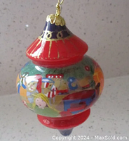 Photo showing the multi-colored hand blown glass Christmas ornament with a festive handpainted scene and gold detailing on top