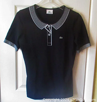 Front view of navy blue Lacoste knit t-shirt with distinctive white striped print collar and cuffs, and embroidered Lacoste crocodile logo on chest