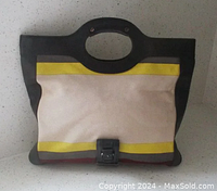 Front view of striped canvas L.A.M.B. clutch with black leather trim, buckle detail and handle