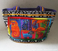 Front view of Laurel Burch Dog Tails medium tote displaying colorful patchwork dog artwork panels with black and white geometric trim.