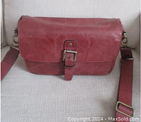 Front view of the burgundy leather Mega Gear camera bag showing the main flap with buckle closure and adjustable crossbody strap.