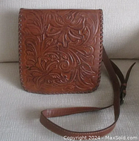 Front view showing detailed tooled floral leather design and strap.