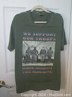 Front view of army green vintage t-shirt featuring We Support Our Troops text in stars and stripes pattern and black and white photo graphic with soldiers.