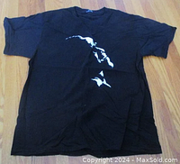 Full view of black short-sleeve T-shirt laid flat showing front graphic of a white artistic silhouette of Ray Charles' face.