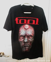 Full view of front of black Tool 2017 North American Tour t-shirt showing red band logo and large detailed gray face artwork by Alex Grey.