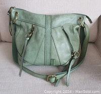 Full front view of the light green sage leather Fossil Monika shoulder bag showing adjustable strap, two diagonal zippered front pockets with tassel pulls, and general bag shape and size.