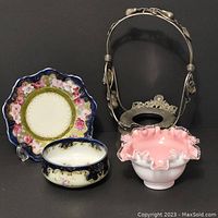 Pink opalescent glass bridal basket with silver stand, blue decorative bowl, and smaller blue bowl.