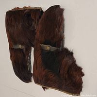 Topside view showing brown beaver fur exterior with snap button adjustment strap on mitts