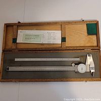 Wooden box containing Mitutoyo dial caliper and certificate of calibration.