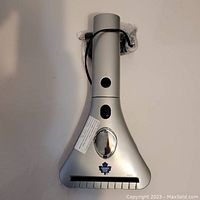 Front view of silver triangular windshield scraper showing power button, power cable wrapped and Toronto Maple Leafs logo.