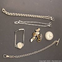 Lot of watch chains, wristwatch, pocket watch face, and keys on black background
