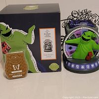 Full view of Scentsy Oogie Boogie warmer next to its box and the included wax bar package.