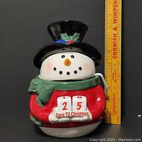 Ceramic snowman warmer with countdown blocks showing '25 Days Til Christmas' with a ruler for scale
