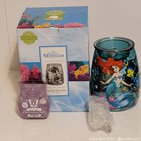 Photo showing the warmer, original box with The Little Mermaid artwork, the 'Welcome Home' scent bar, and the light bulb wrapped in bubble wrap.