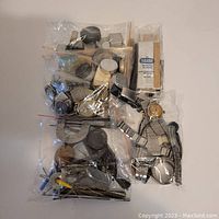 Mixed bags containing assorted watch parts, tools, and bracelets shown from above