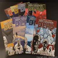Eight volumes of The Walking Dead graphic novels, covers visible showing title and artwork of zombies and survivors.