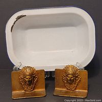 Front view of white enamelware oblong tray with two vintage steel bookends featuring gold-tone chef heads in front and slightly to the sides.