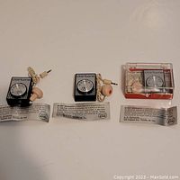 Three vintage Clairtone mini transistor AM radios laid out showing dial, earbud, and warranty paper beneath each.