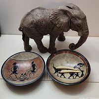 Elephant statue and two soapstone bowls shown together with African style artwork.