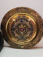 Full view of the round copper wall plate showing colorful Mayan symbols and intricate circular design.