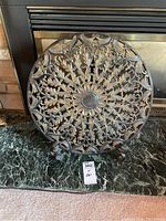 Front view of the decorative metal plate showing detailed floral and leaf embossed designs with central flower motif.