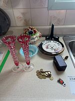 Wide view showing ruby glass vases, ceramic floral piece, blue bowl, decorative plate with dog image, coin bracelet, purple trinket box, and small items.
