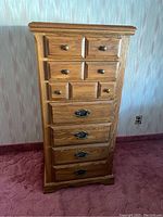 Front view of the Palliser seven drawer wooden dresser with round and decorative metal hardware.