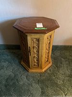 Front and side view of the octagonal end table with cabinet door and carved panels.