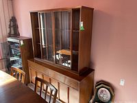 Front view of two-piece wood hutch showing top glass display cabinet with three sliding doors and bottom storage base