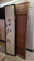 Two room dividers side by side: one bamboo print with black frame and one woven rattan panel