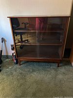 Front view of the vintage wooden shelf with sliding glass doors, showing the overall structure and legs.