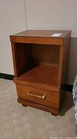 Front and angled view of the vintage wood night table, showing the open shelf and drawer with brass handle.
