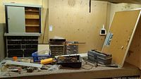 Wide shot of workshop counter with metal storage cabinets, corkboard, and assorted tools and hardware on counter
