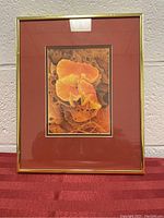 Framed picture with orange and yellow mushrooms, autumn leaves, reddish-brown mat and thin gold frame.