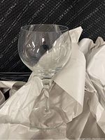 Close-up of a single clear glass stemware wrapped in white paper on a dark background
