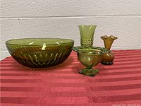 Four green glass decorative pieces on red fabric with white brick wall background