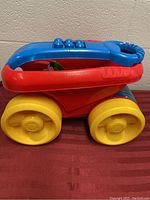 Side view of the red wagon with yellow wheels and blue top showing the pull handle and block connector design.