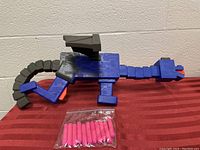 Photo showing full view of the Nerf Minecraft Ender Dragon blaster with pink foam darts set in front.