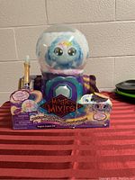 Full view of the Magic Mixies Magical Crystal Ball toy in its packaging on a red table.