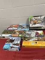 Lot of 8 assorted 1000 piece puzzles with various scenic themes, includes one Marvel puzzle new in package