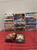 Photo showing a stacked collection of over 35 VHS tapes with a variety of titles including Disney classics and family movies.