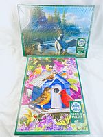 Two boxed Cobble Hill jigsaw puzzles with bird scenes: one sealed Common Loons and one Spring Birdhouse with visible brand and piece count