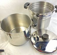 Three-piece Lagostina pasta pot set showing pot, perforated insert, and lid with black knob and handles.