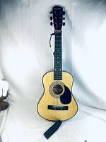 Full front view of the children's acoustic guitar showing the light wood finish, black pickguard, black bridge, and Kawasaki logo on the headstock.